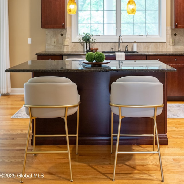 1 Arbor Dr, Guilderland, NY 12159 - kitchen with a kitchen bar, light wood-style floors, backsplash, and dark stone countertops