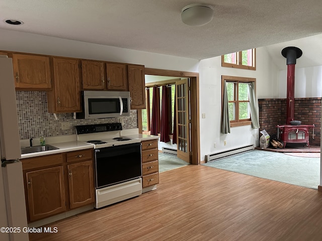 11 Ridgecrest Way, Hampton, NY 12887 - kitchen featuring stainless steel microwave, range with electric cooktop, a baseboard radiator, a wood stove, and freestanding refrigerator
