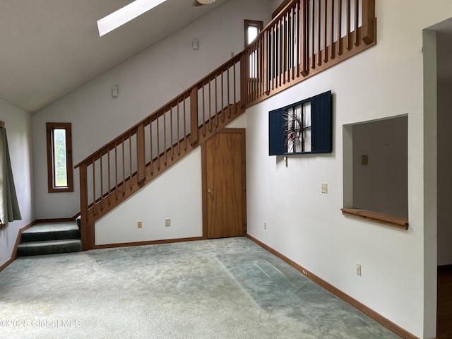11 Ridgecrest Way, Hampton, NY 12887 - unfurnished living room featuring stairs, carpet floors, high vaulted ceiling, and a skylight