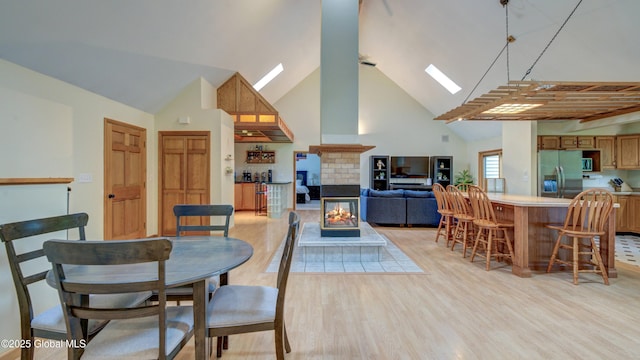 324 Elsmere Ave, Bethlehem, NY 12054 - dining room with a skylight, high vaulted ceiling, light wood-type flooring, and a brick fireplace