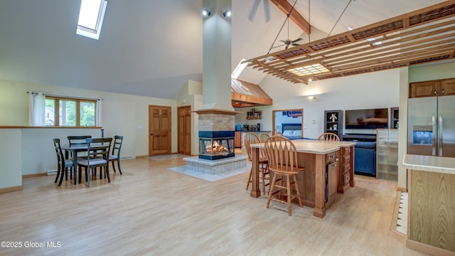 324 Elsmere Ave, Bethlehem, NY 12054 - kitchen with stainless steel fridge with ice dispenser, high vaulted ceiling, a tiled fireplace, open floor plan, and light countertops