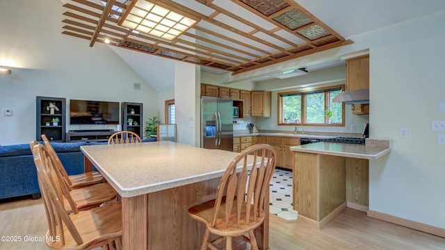 324 Elsmere Ave, Bethlehem, NY 12054 - kitchen with stainless steel fridge, a breakfast bar, light countertops, plenty of natural light, and high vaulted ceiling