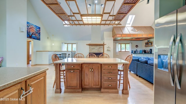 324 Elsmere Ave, Bethlehem, NY 12054 - kitchen with stainless steel fridge with ice dispenser, open floor plan, a high ceiling, a breakfast bar, and light wood finished floors