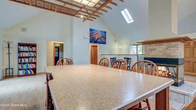 324 Elsmere Ave, Bethlehem, NY 12054 - dining area with high vaulted ceiling, a fireplace, a skylight, and light wood finished floors