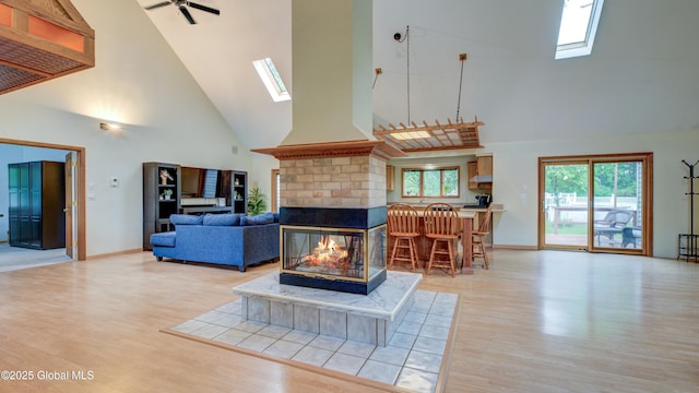 324 Elsmere Ave, Bethlehem, NY 12054 - living area featuring high vaulted ceiling, a skylight, light wood-type flooring, a fireplace, and ceiling fan