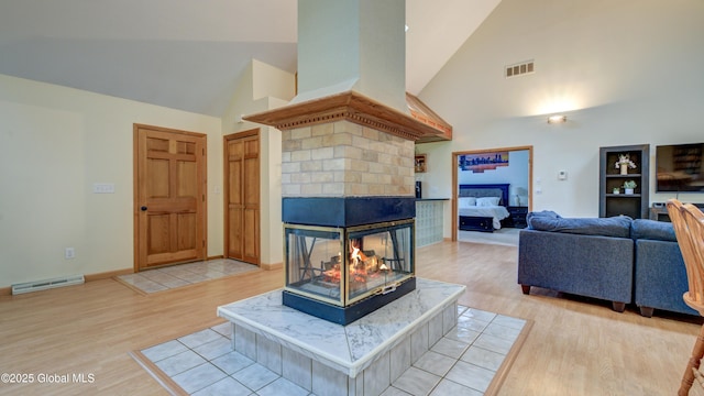 324 Elsmere Ave, Bethlehem, NY 12054 - living room featuring high vaulted ceiling, light wood-type flooring, a multi sided fireplace, and a baseboard radiator