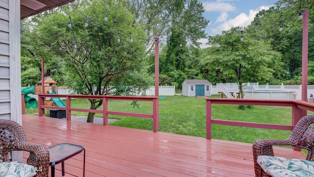324 Elsmere Ave, Bethlehem, NY 12054 - wooden deck featuring a playground, a fenced backyard, a storage unit, and view of wooded area
