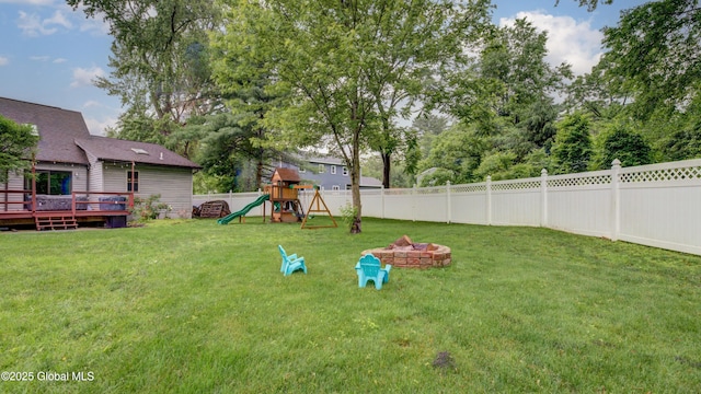 324 Elsmere Ave, Bethlehem, NY 12054 - fenced backyard with a playground, a wooden deck, and an outdoor fire pit
