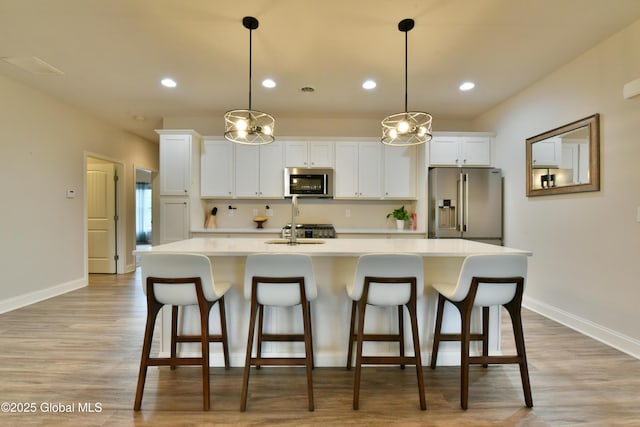 16 Anthony Pl, Ballston, NY 12020 - kitchen with appliances with stainless steel finishes, a center island with sink, light countertops, white cabinets, and light wood-type flooring