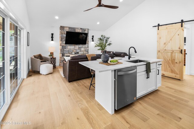 19 Forest Rd, Queensbury, NY 12845 - kitchen with stainless steel dishwasher, a barn door, light wood-style flooring, vaulted ceiling, and a center island with sink
