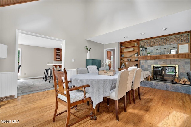1 Fox Run, Colonie, NY 12110 - dining room featuring a tiled fireplace, wood finished floors, built in shelves, a wainscoted wall, and a high ceiling