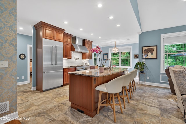 6 Corinne Ct, Saratoga, NY 12866 - kitchen featuring wall chimney exhaust hood, stainless steel built in refrigerator, crown molding, light stone countertops, and a kitchen bar