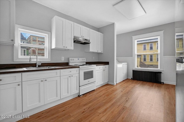 329 E Main St, Amsterdam, NY 12010 - kitchen with radiator, white electric range oven, under cabinet range hood, dark countertops, and light wood-style floors