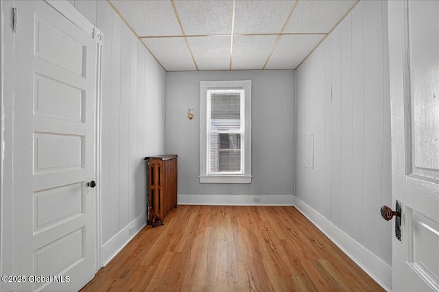 329 E Main St, Amsterdam, NY 12010 - spare room featuring light wood-style flooring, a paneled ceiling, and radiator heating unit