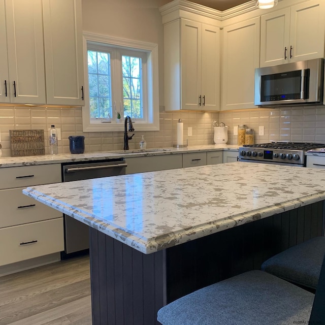 1E Brison St, North Greenbush, NY 12180 - kitchen featuring appliances with stainless steel finishes, light wood-type flooring, white cabinets, decorative backsplash, and light stone counters