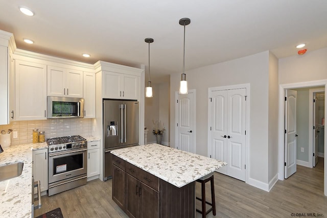 1E Brison St, North Greenbush, NY 12180 - kitchen featuring premium appliances, light wood-type flooring, backsplash, white cabinetry, and recessed lighting
