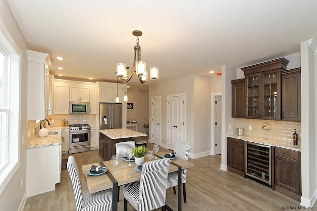 1E Brison St, North Greenbush, NY 12180 - dining space with beverage cooler, light wood-type flooring, bar with sink, recessed lighting, and a chandelier