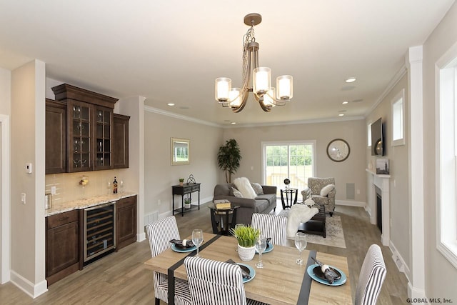 1E Brison St, North Greenbush, NY 12180 - dining space featuring beverage cooler, wet bar, a chandelier, a fireplace, and light wood finished floors