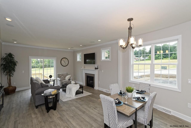 1E Brison St, North Greenbush, NY 12180 - dining room with a glass covered fireplace, light wood-style floors, a chandelier, crown molding, and recessed lighting