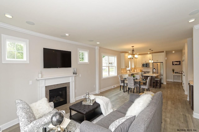 1E Brison St, North Greenbush, NY 12180 - living area featuring a chandelier, light wood-type flooring, crown molding, a glass covered fireplace, and recessed lighting