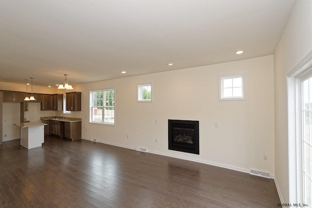 1E Brison St, North Greenbush, NY 12180 - unfurnished living room featuring a chandelier, plenty of natural light, dark wood-type flooring, and recessed lighting