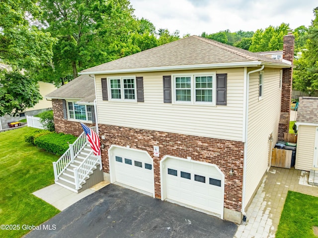 34 Aspen Rd, Colonie, NY 12110 - tri-level home featuring a garage, driveway, a chimney, a front yard, and brick siding