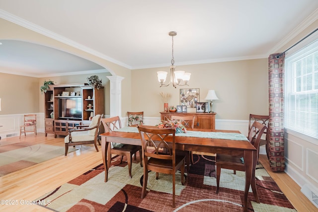 34 Aspen Rd, Colonie, NY 12110 - dining area with light wood-style flooring, a chandelier, arched walkways, ornamental molding, and wainscoting