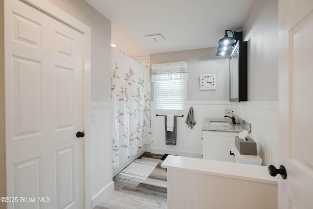 34 Aspen Rd, Colonie, NY 12110 - bathroom with vanity, wood finished floors, a shower with shower curtain, a wainscoted wall, and a decorative wall
