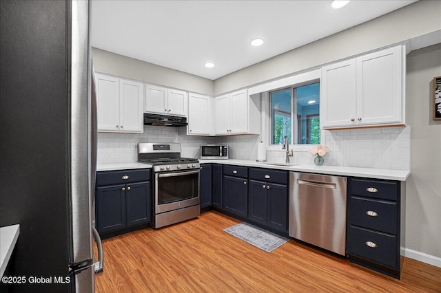 5 Pine Crst, Malta, NY 12019 - kitchen with stainless steel appliances, under cabinet range hood, white cabinetry, light wood finished floors, and light countertops