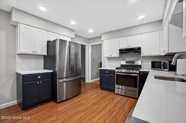 5 Pine Crst, Malta, NY 12019 - kitchen with appliances with stainless steel finishes, range hood, white cabinets, light wood-style floors, and tasteful backsplash