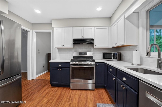 5 Pine Crst, Malta, NY 12019 - kitchen featuring stainless steel appliances, under cabinet range hood, white cabinetry, light countertops, and light wood-type flooring