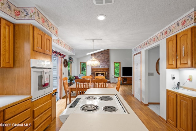 69 Deer Run Holw, Halfmoon, NY 12065 - kitchen with vaulted ceiling, light wood-type flooring, a textured ceiling, light countertops, and oven