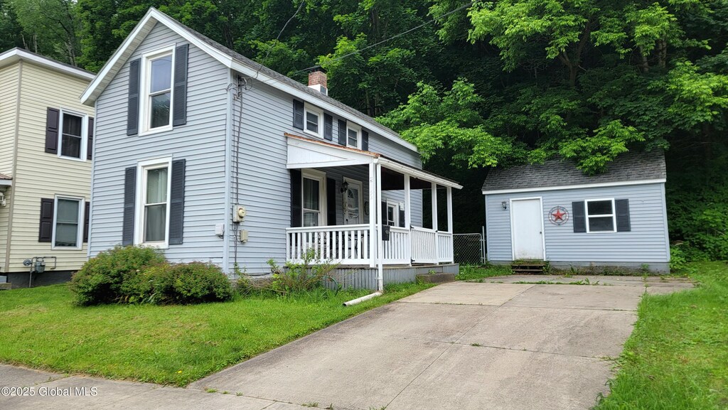 52 Hancock St, Fort Plain, NY 13339 - view of front of property featuring covered porch, a front yard, a chimney, and an outdoor structure