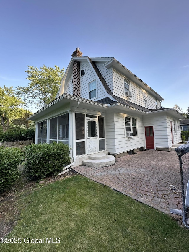 945 Morgan Ave, Niskayuna, NY 12309 - view of front of home featuring a chimney, a sunroom, a patio, a gambrel roof, and a front lawn