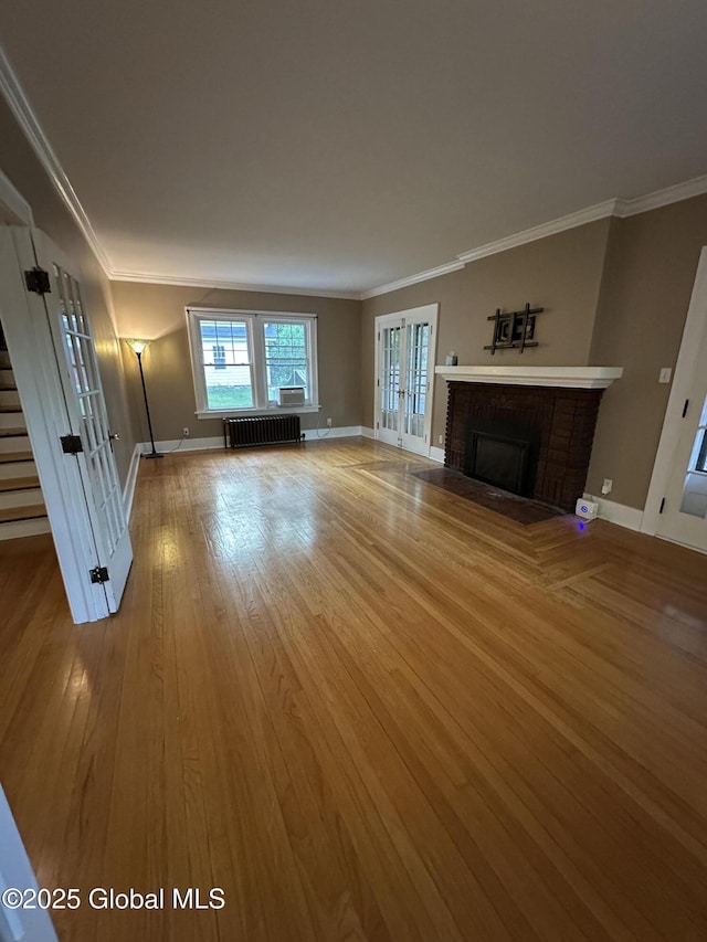 945 Morgan Ave, Niskayuna, NY 12309 - unfurnished living room featuring radiator, a brick fireplace, wood finished floors, crown molding, and stairs