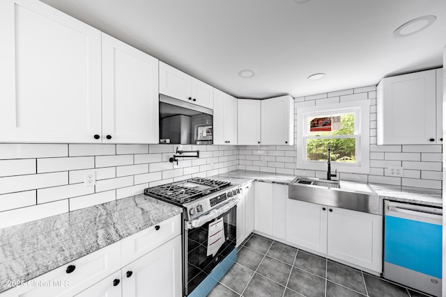 92 Central Ave, Rensselaer, NY 12144 - kitchen with appliances with stainless steel finishes, decorative backsplash, white cabinetry, dark tile patterned flooring, and light stone countertops