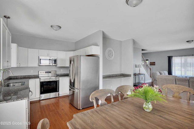9 Sebring Ave, Colonie, NY 12205 - kitchen featuring appliances with stainless steel finishes, dark stone counters, open floor plan, white cabinets, and dark wood-style flooring
