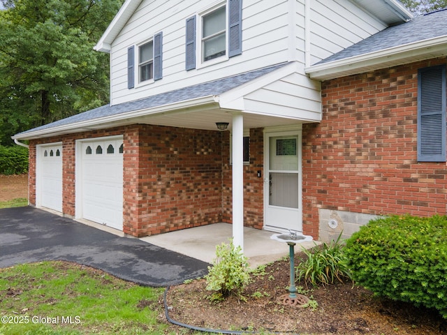 5012 Juniper Ln, Guilderland, NY 12303 - property entrance with covered porch, brick siding, a garage, and a shingled roof