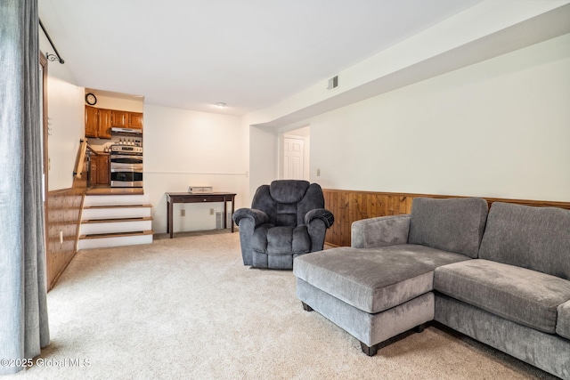 5012 Juniper Ln, Guilderland, NY 12303 - living room with wood walls, wainscoting, light colored carpet, and stairway