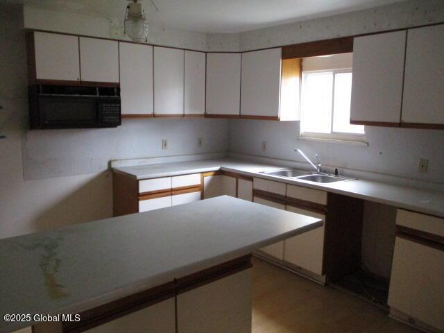 12 Chestnut St, Gloversville, NY 12078 - kitchen with black microwave, white cabinetry, white dishwasher, and light countertops