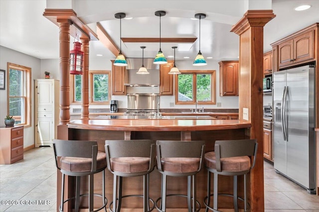 1062 S S Shore Rd, Hadley, NY 12835 - kitchen with stainless steel fridge, ornate columns, a kitchen island with sink, light tile patterned floors, and recessed lighting