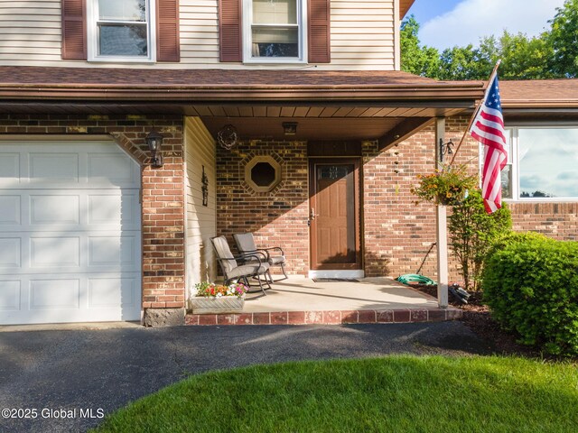 23 Tokay Ln, Colonie, NY 12309 - view of exterior entry featuring brick siding, covered porch, and a garage