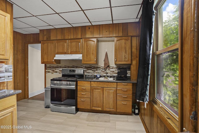 2303 Burdett Ave, Troy, NY 12180 - kitchen featuring stainless steel range with gas cooktop, under cabinet range hood, tasteful backsplash, brown cabinets, and a paneled ceiling