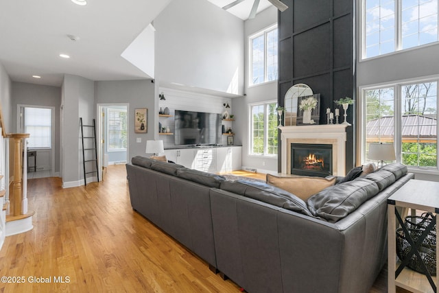 11 Fairview Ln, Halfmoon, NY 12118 - living room with light wood-style floors, a glass covered fireplace, recessed lighting, a high ceiling, and ceiling fan