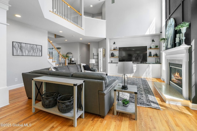 11 Fairview Ln, Halfmoon, NY 12118 - living room with a towering ceiling, stairs, wood finished floors, and a glass covered fireplace
