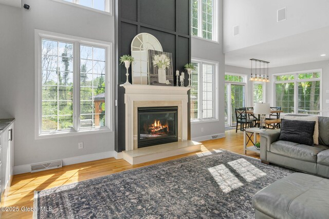 11 Fairview Ln, Halfmoon, NY 12118 - living room with healthy amount of natural light, light wood-type flooring, a high ceiling, and a glass covered fireplace