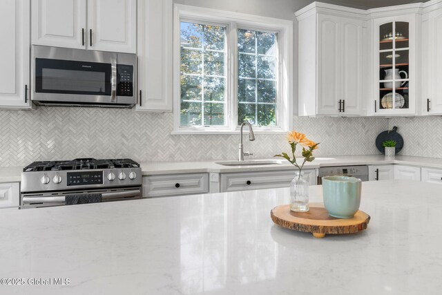 11 Fairview Ln, Halfmoon, NY 12118 - kitchen featuring appliances with stainless steel finishes, white cabinets, glass insert cabinets, backsplash, and light stone countertops