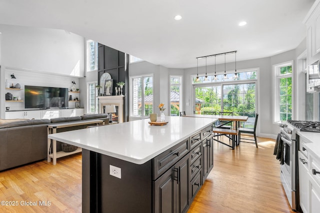 11 Fairview Ln, Halfmoon, NY 12118 - kitchen featuring stainless steel gas range, light countertops, a glass covered fireplace, light wood-style flooring, and recessed lighting