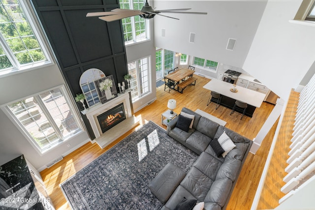 11 Fairview Ln, Halfmoon, NY 12118 - living area featuring ceiling fan, a towering ceiling, plenty of natural light, wood finished floors, and a glass covered fireplace