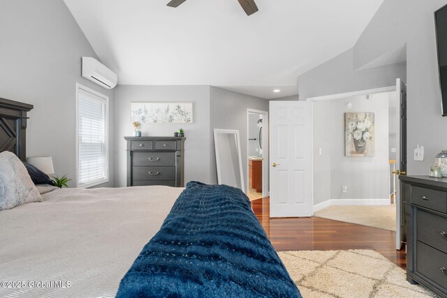 11 Fairview Ln, Halfmoon, NY 12118 - bedroom featuring a wall unit AC, vaulted ceiling, wood finished floors, a ceiling fan, and ensuite bathroom